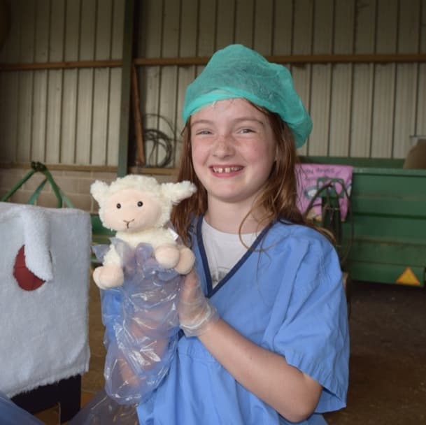 A Young Vet member smiling as they hold a recent "patient" - a toy sheep